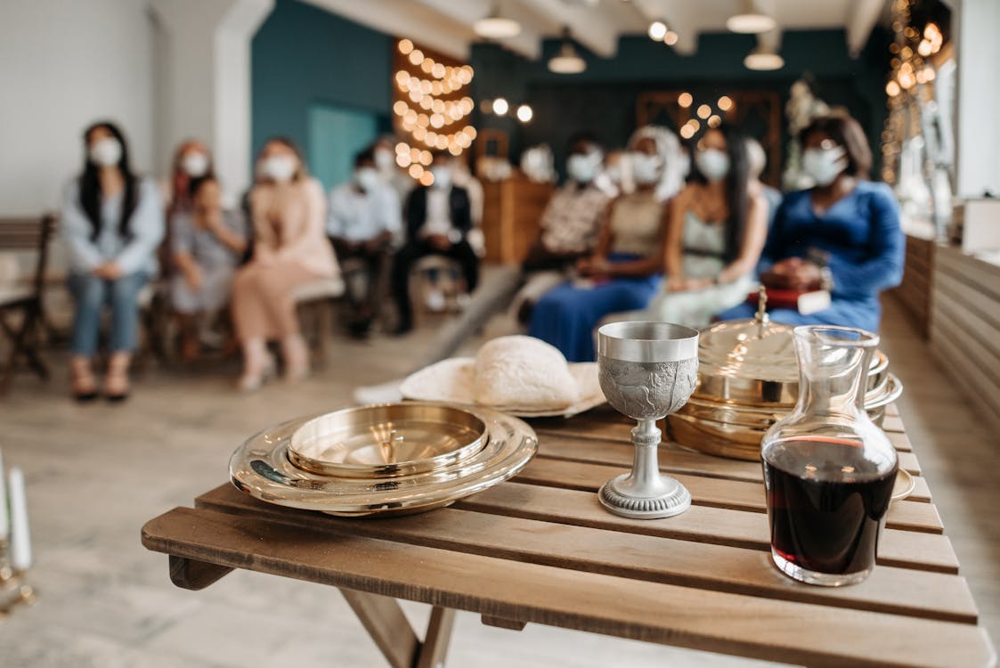 Free Communion Trays and Chalice Beside a Wine in Bottle on Brown Wooden Table Stock Photo