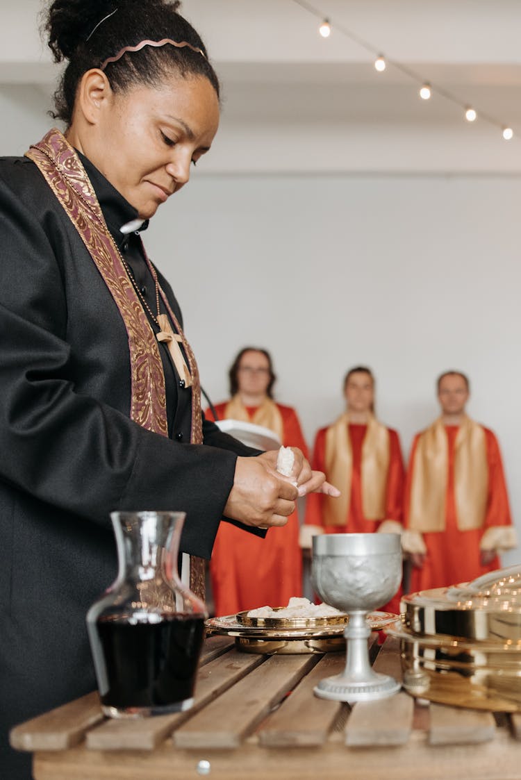 A Pastor Breaking Bread Beside A Wooden Table