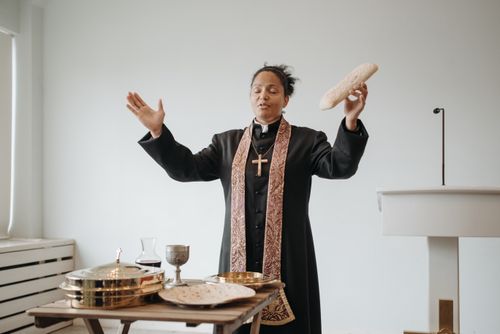 Free A female pastor leads a communion ceremony indoors, holding sacramental bread. Stock Photo