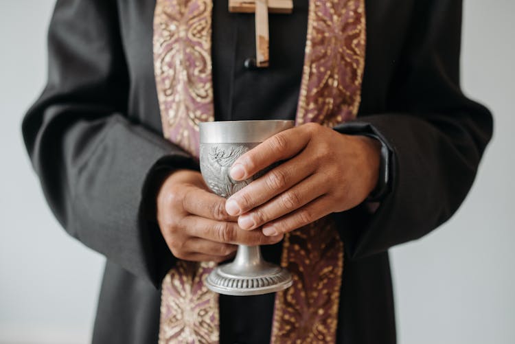 A Priest Holding A Silver Chalice