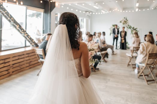 Bride approaches altar during an indoor ceremony with guests and floral decor.