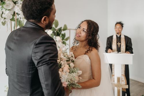 Free A touching wedding ceremony featuring a bride and groom exchanging vows indoors with a pastor officiating. Stock Photo