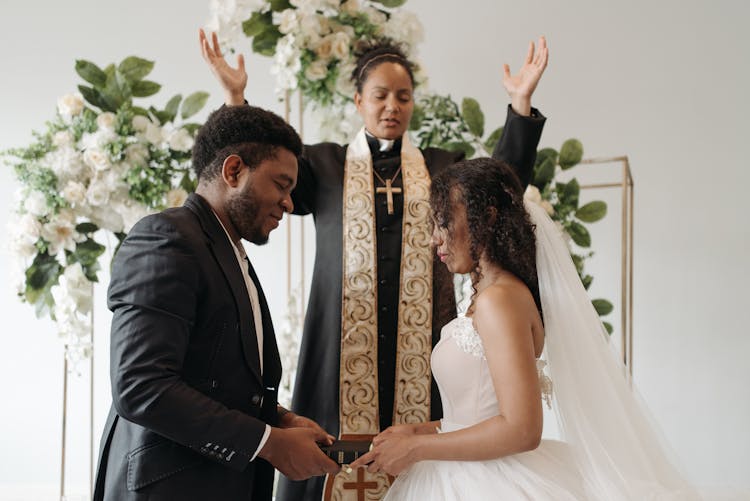 A Woman Pastor Giving Blessing To The Newlyweds