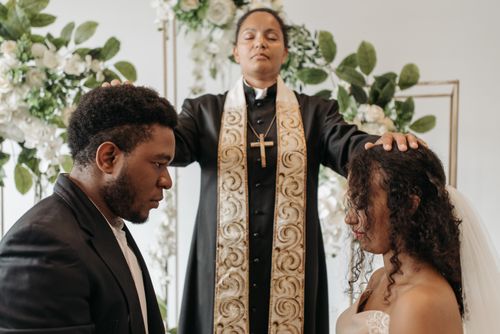 Free A serene wedding ceremony with a woman pastor officiating over a couple indoors. Stock Photo