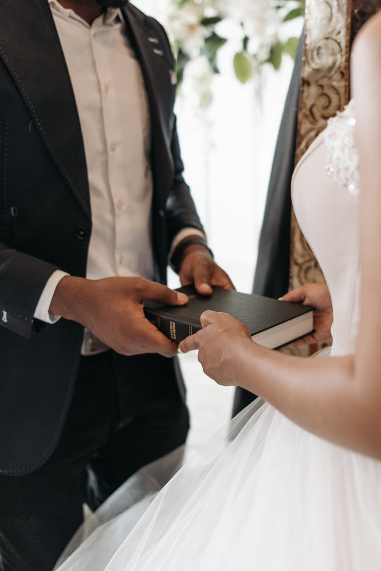 A Bride And Groom Holding A Bible