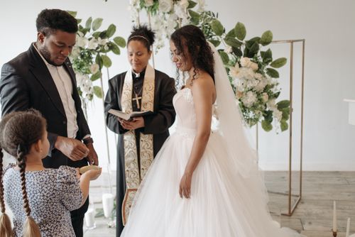 Free A beautiful indoor wedding ceremony with bride, groom, and officiant exchanging vows. Stock Photo