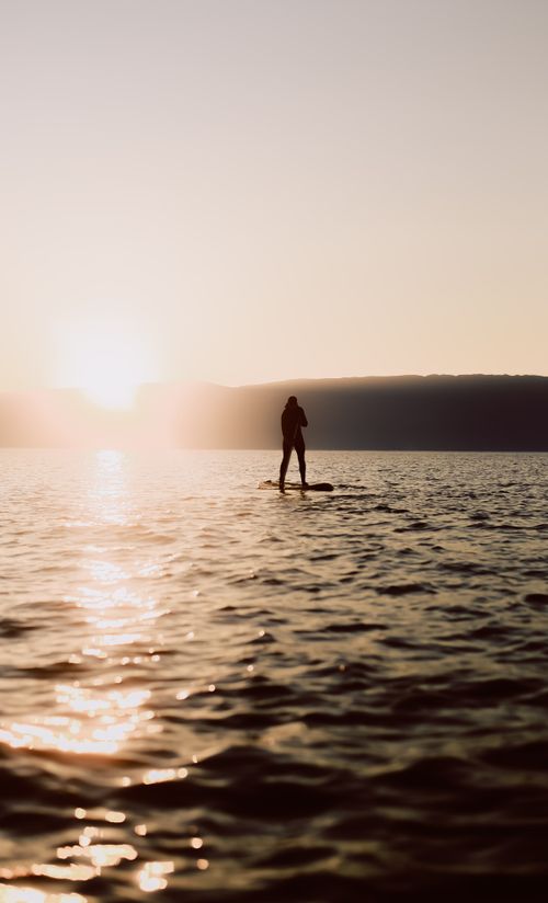 Free Scenic silhouette of a paddleboarder at sunrise over Lake Baikal, Russia, capturing tranquility and adventure. Stock Photo