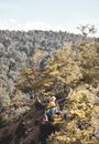 Man in Blue Shirt and Brown Shorts With Backpack Standing on Rocky Hill