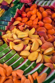 Colorful array of freshly sliced watermelon, apricots, and other fruits. Perfect for healthy eating and food photography.
