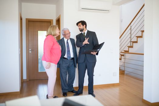 Realtor showing property to senior couple inside a modern home in Portugal.