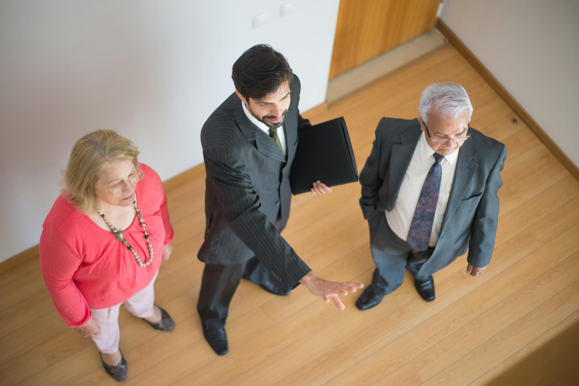 A realtor shows a property to a senior couple in a modern indoor setting.