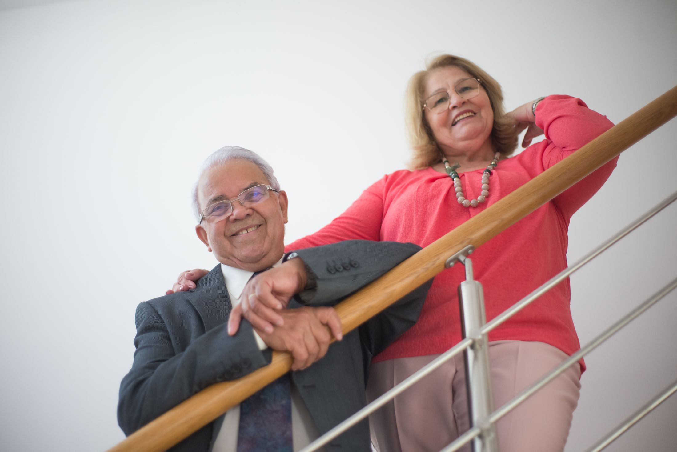 A happy older couple standing together on a bright contemporary staircase at home