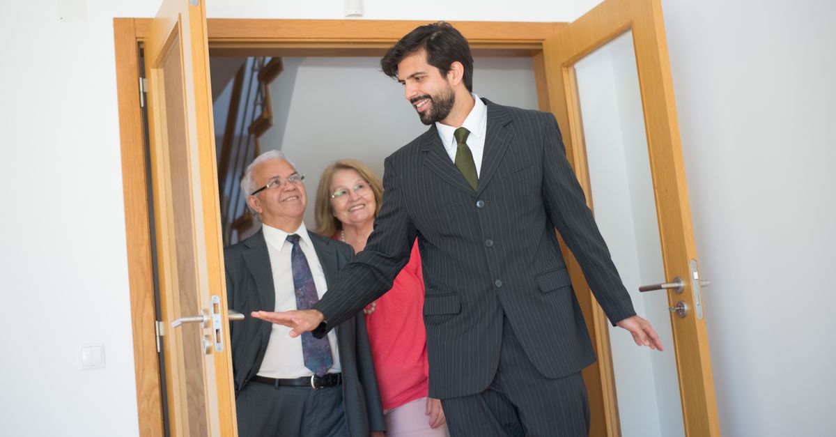 Smiling real estate agent showing an elegant home to a senior couple. Indoor setting in Portugal.