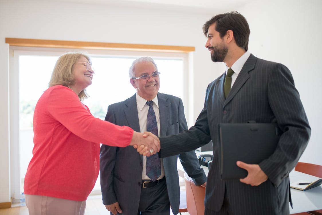 Real estate industry professional shaking hands with a woman who just sold her home. 