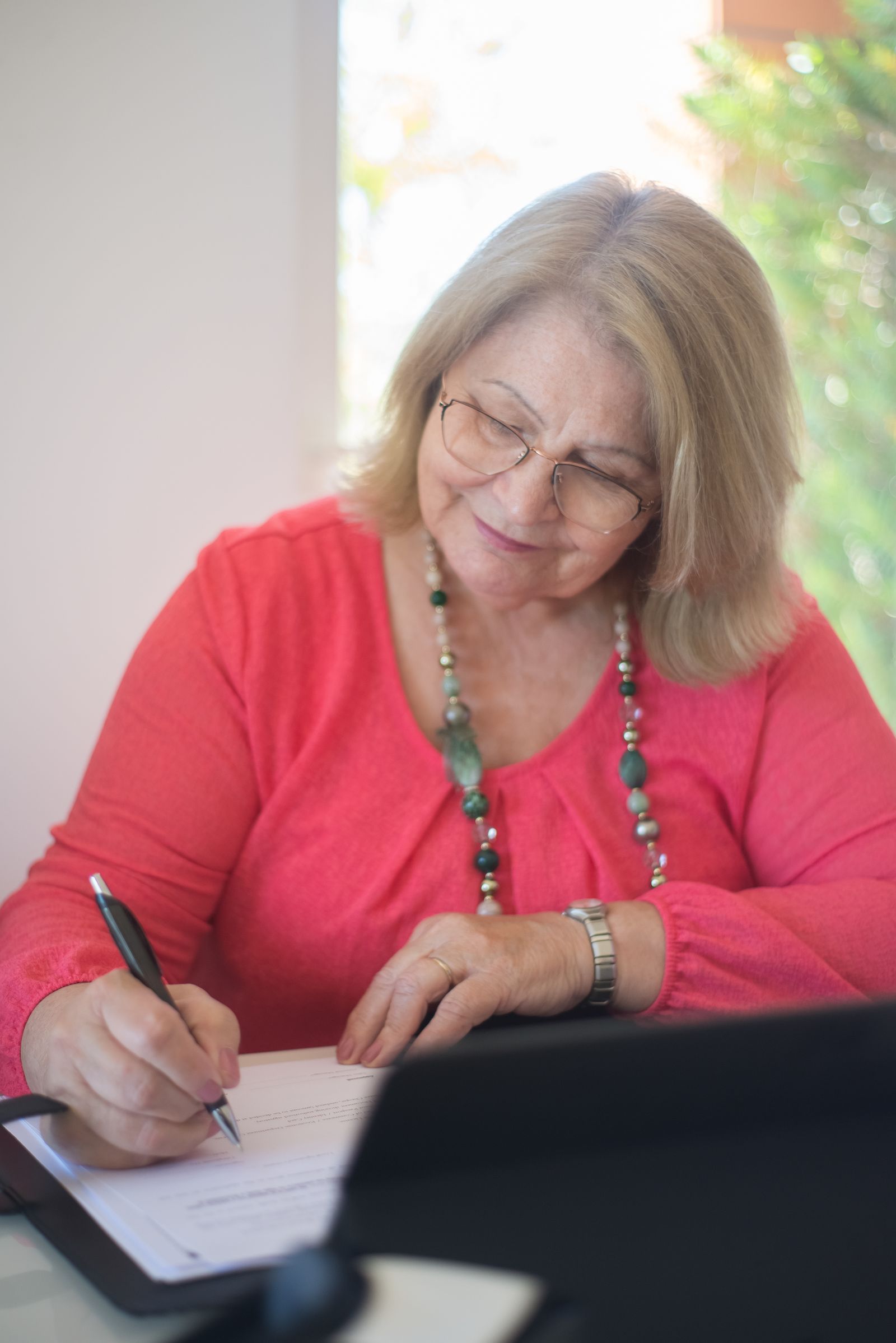 Donna che firma documenti seduta a un tavolo