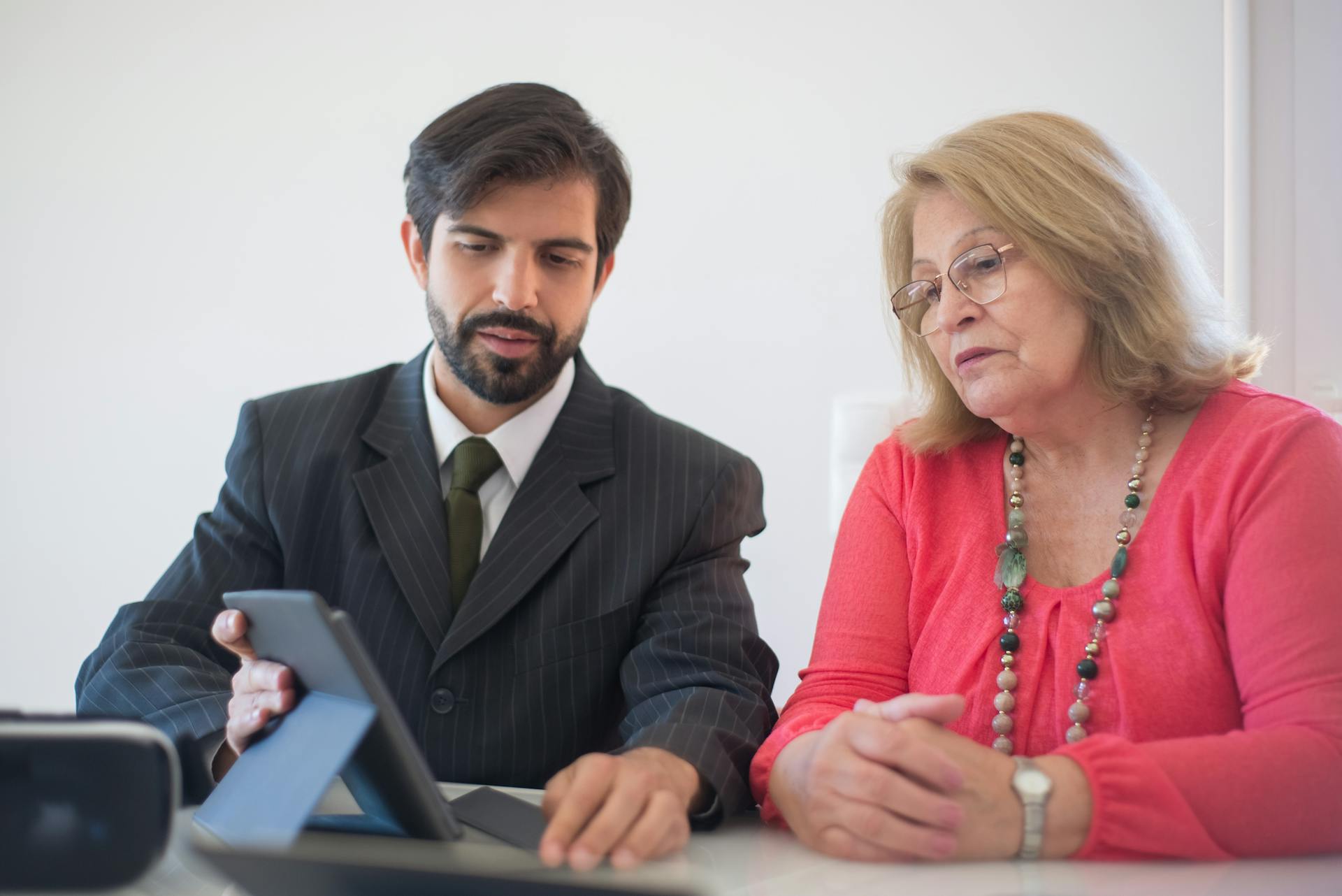 Business meeting in Portugal between a man and senior woman discussing with tablet.