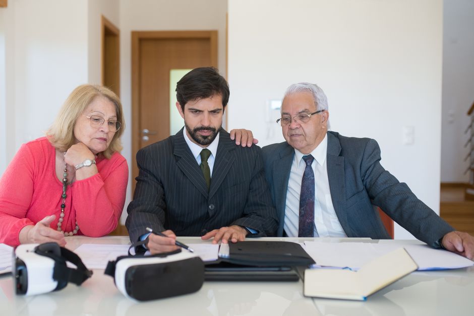 An older adult couple planning at a kitchen table with papers and a coffee mug, illustrating calm, clear planning for safeguarding shared custody, child support, and finances post-separation.. Captured by Kampus Production