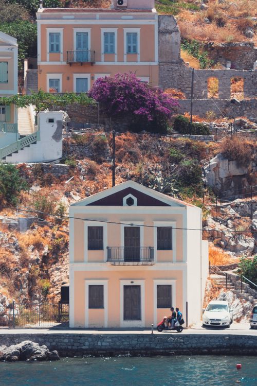 Free Picturesque view of traditional houses by the sea in Ano Symi, Greece. Stock Photo