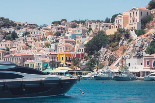 Free A picturesque view of colorful homes on the Symi hillside overlooking a serene harbor filled with yachts. Stock Photo