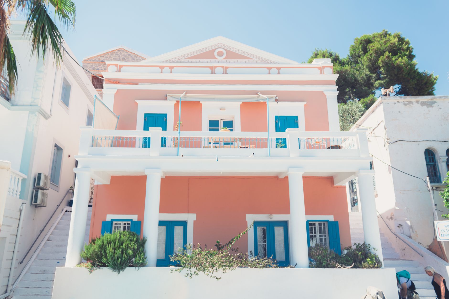 Neoclassical houses along the waterfront of Spetses town, with masts and boats on the water.