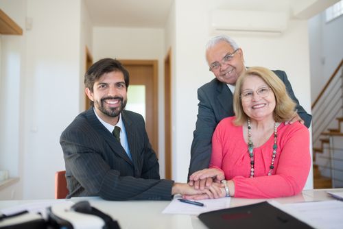 Free Smiling senior couple meeting with a professional advisor in a bright indoor setting. Stock Photo