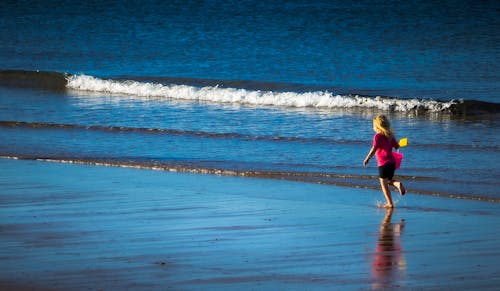 Girl in a Pink Shirt Running at the Beach