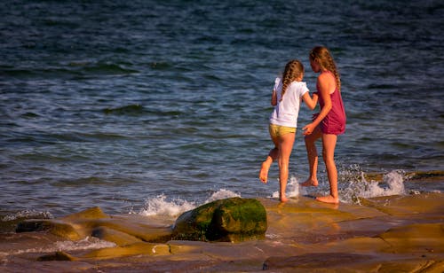 Photo of Girls Playing Near the Sea