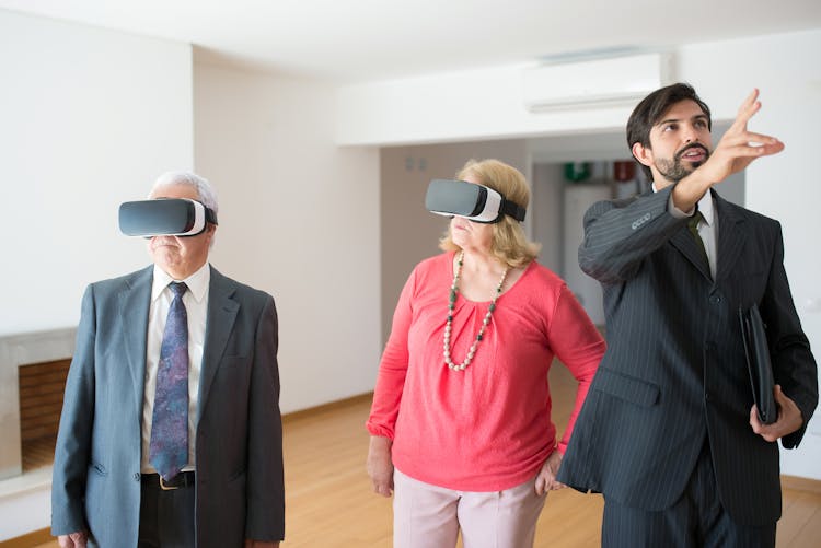 A Real Estate Agent Explaining Things To A Two Seniors Wearing VR Goggles