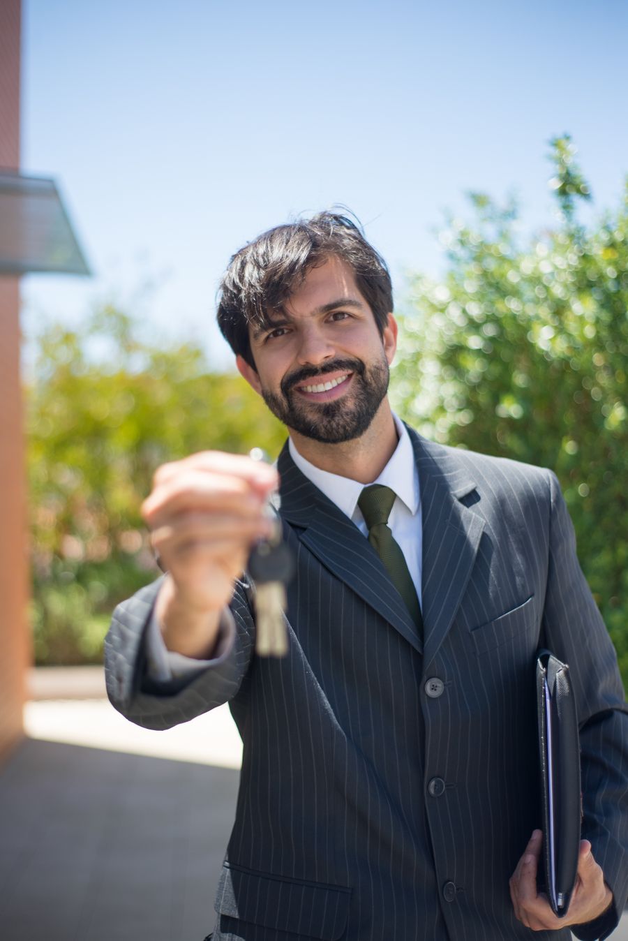 Habitat real estate agent in a suit handing over house keys outdoors