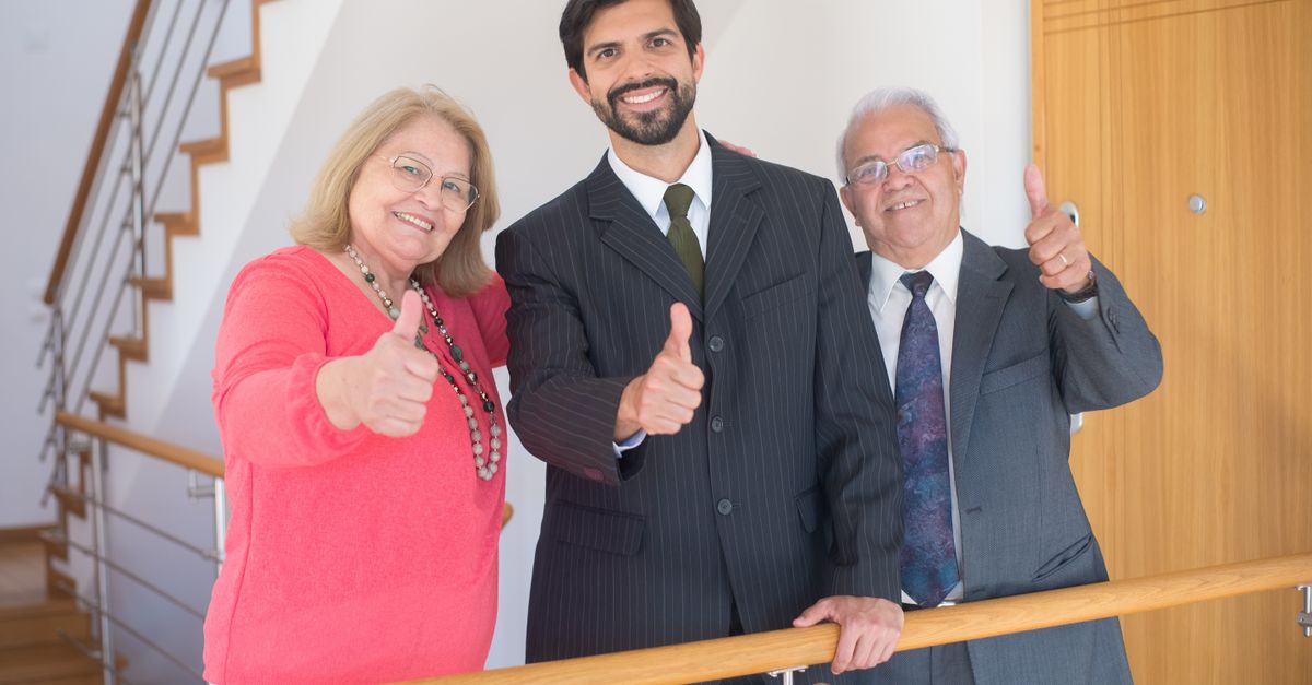 Three business professionals giving thumbs up in an indoor setting, symbolizing success and agreement.