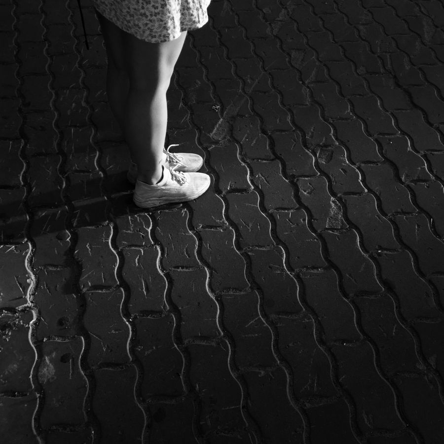 Legs and worn sneakers on a cobblestone street at night — photo by Ivan Xolod on Pexels
