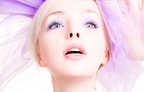 Free Close-up portrait of a woman with lavender makeup and ethereal tulle background. Stock Photo