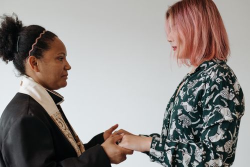 Free A priest and a woman standing indoors, holding hands in a ritualistic gesture, symbolizing unity and faith. Stock Photo