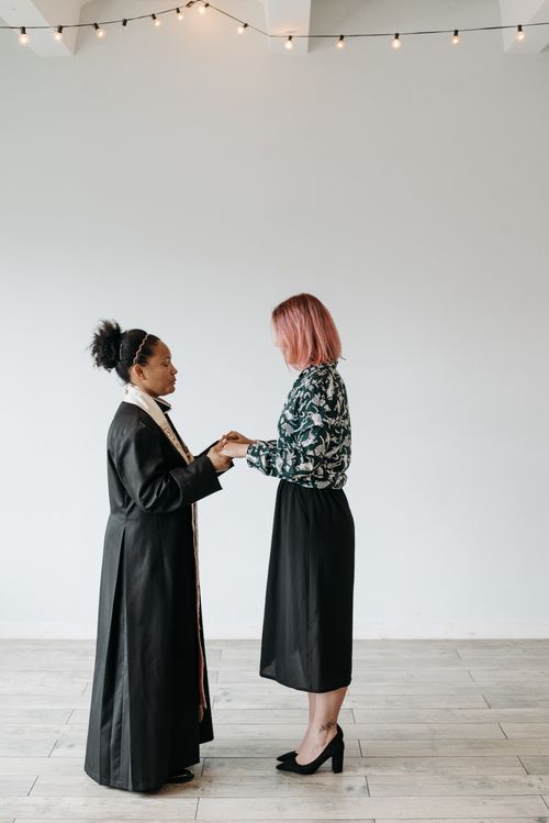 Free A diverse pair of women holding hands in a minimalist indoor setting. Stock Photo