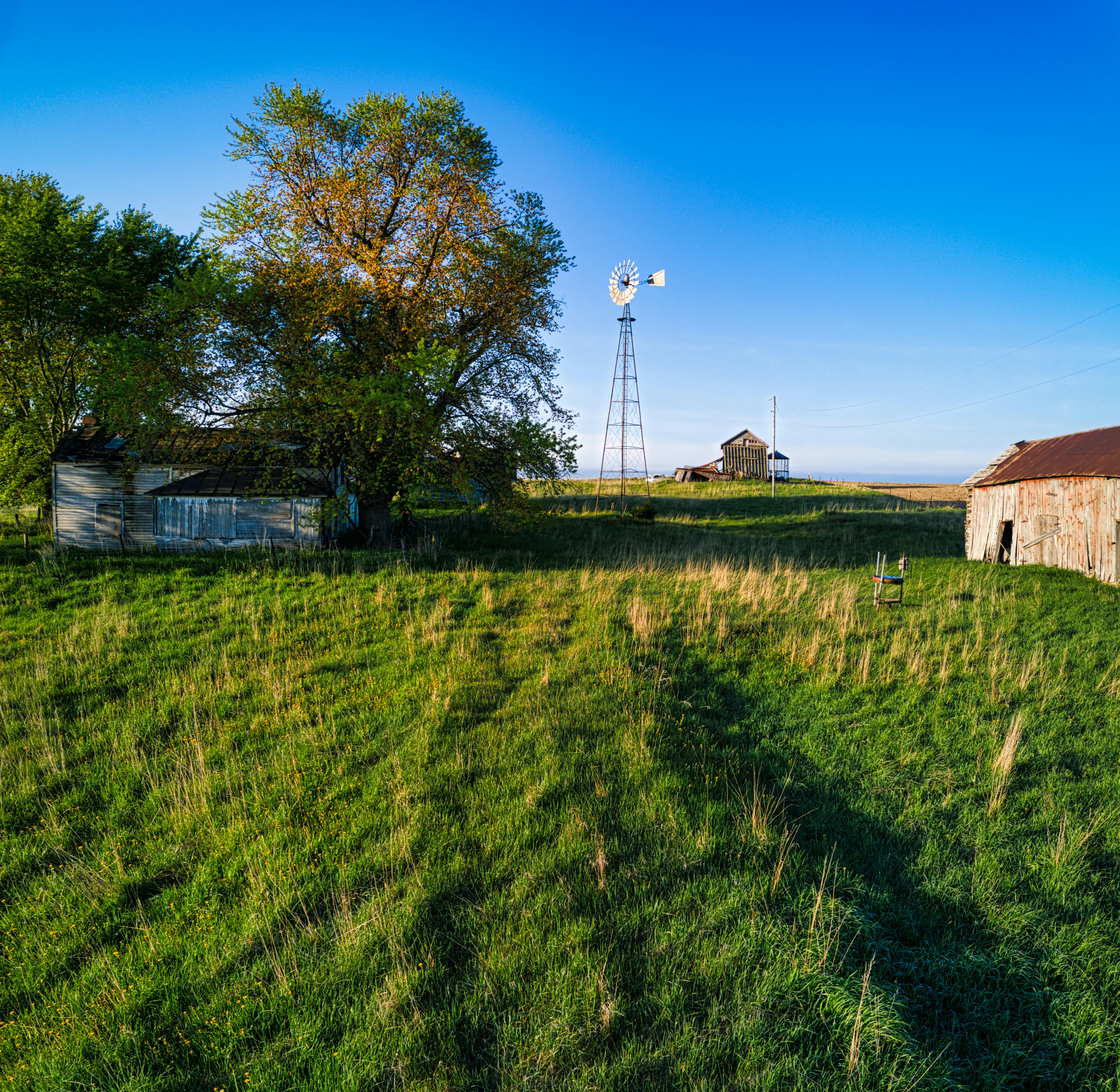 A serene summer landscape with a traditional windmill and rustic farm buildings in Minnesota.