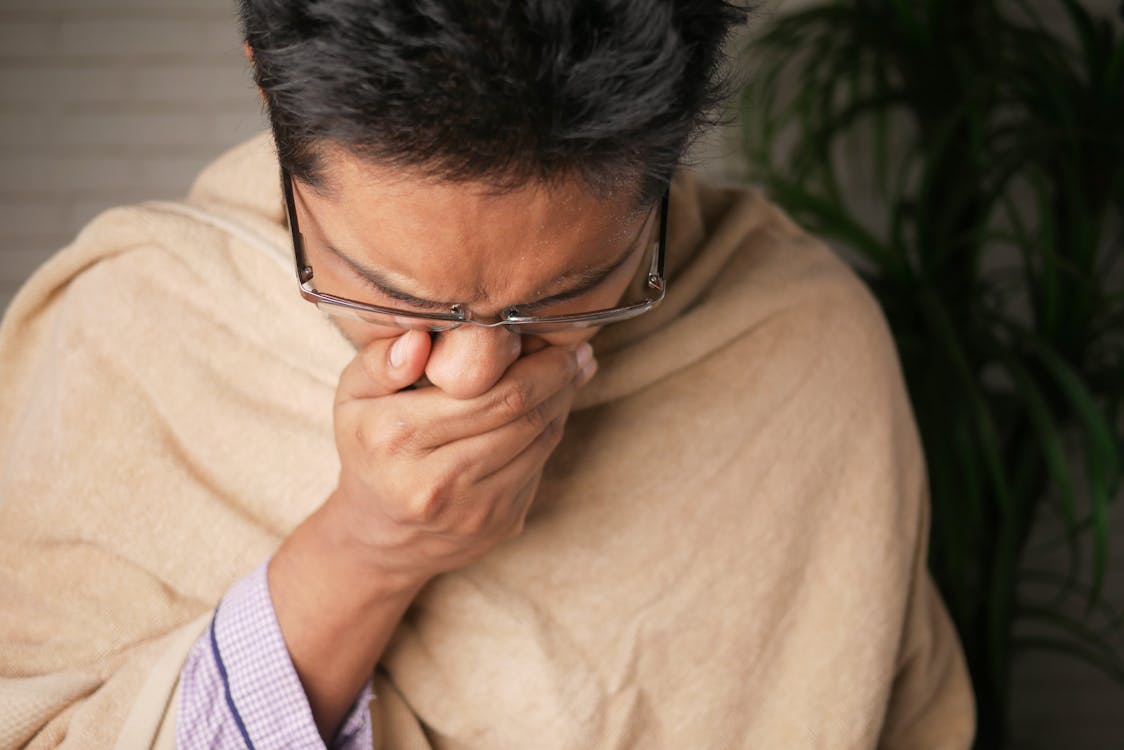 Close-Up Photo of a Sick Man Covering His Mouth