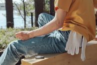 Person in Blue Denim Jeans Sitting on Brown Wooden Bench