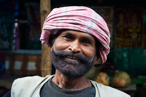 男人穿著粉紅色的頭巾頭飾微笑