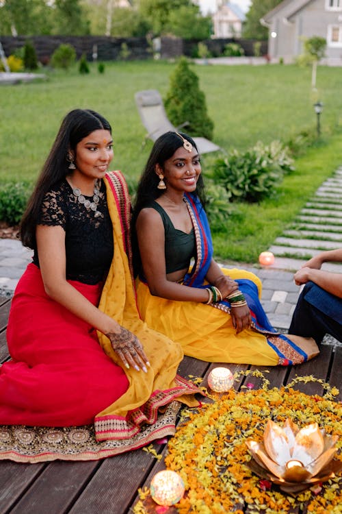 Young Women Smiling and Sitting in their Traditional Clothing on a Garden