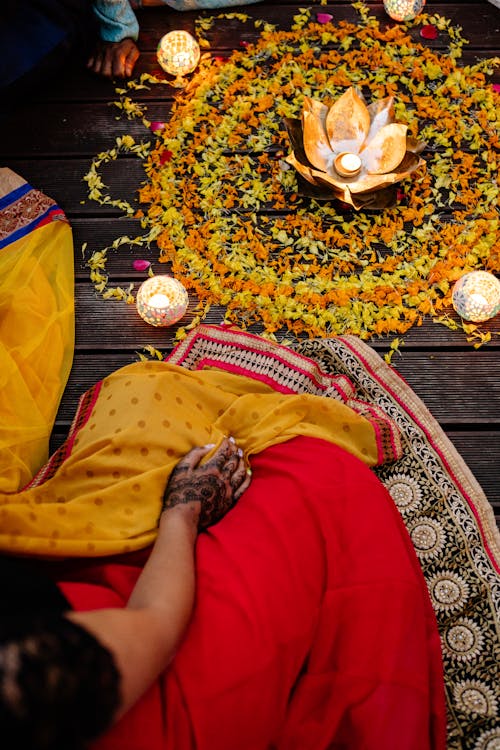 Person Sitting in Front of a Flower Arrangement Wearing a Traditional Clothes 