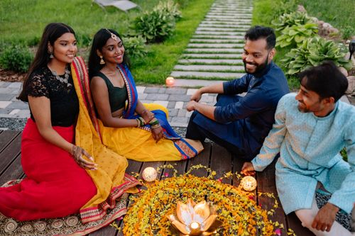 Free A group of Indian adults sitting and smiling in traditional attire, celebrating Diwali with a flower garland arrangement. Stock Photo