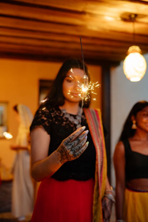 Free Young woman with henna holds a sparkler indoors during Diwali celebration. Stock Photo