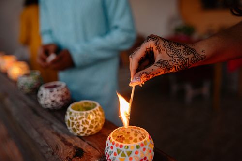 Free A hand with henna tattoos lights a candle during a Diwali celebration, showcasing festive traditions. Stock Photo