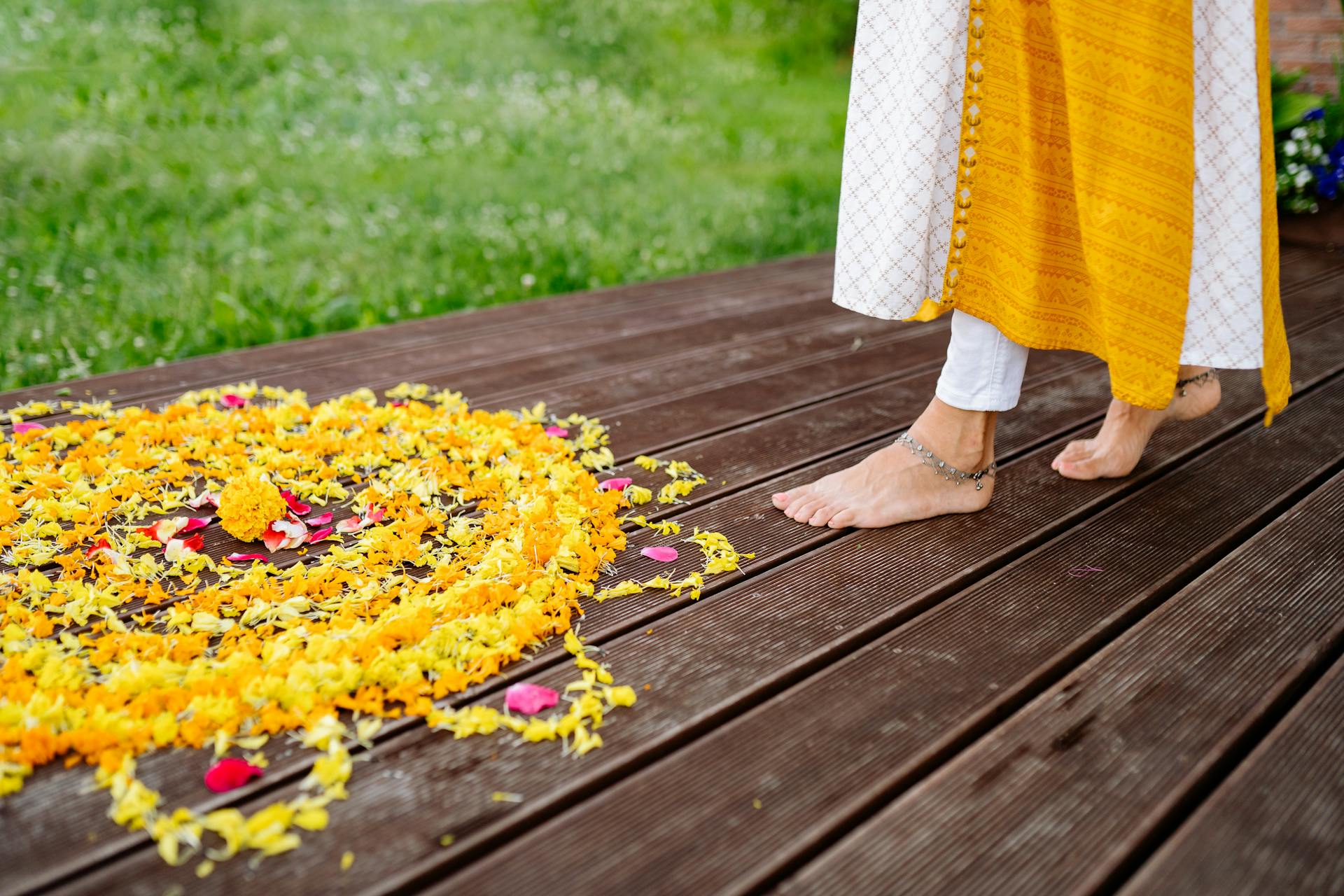 A person dressed in traditional attire walking barefoot on wooden flooring with intricate flower petal design.