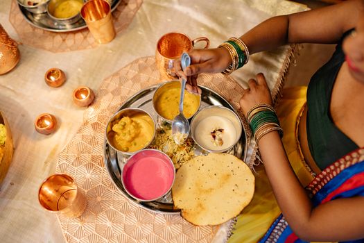 Vibrant Indian thali served during festive occasion with traditional diyas and attire.