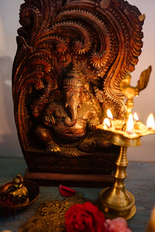 Golden Ganesha Beside Lighted Candles on a Wooden Surface