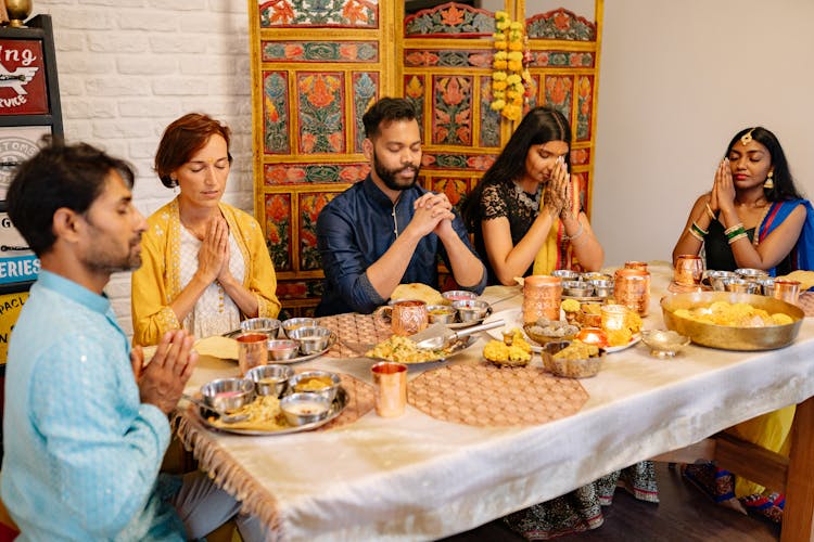 Group Of People Praying In Front Of The Table