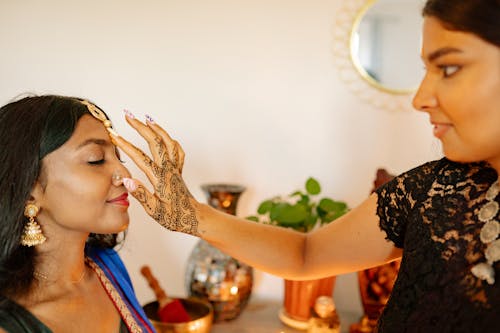 A Tattooed Woman Putting Bindi on Another Woman's Forehead