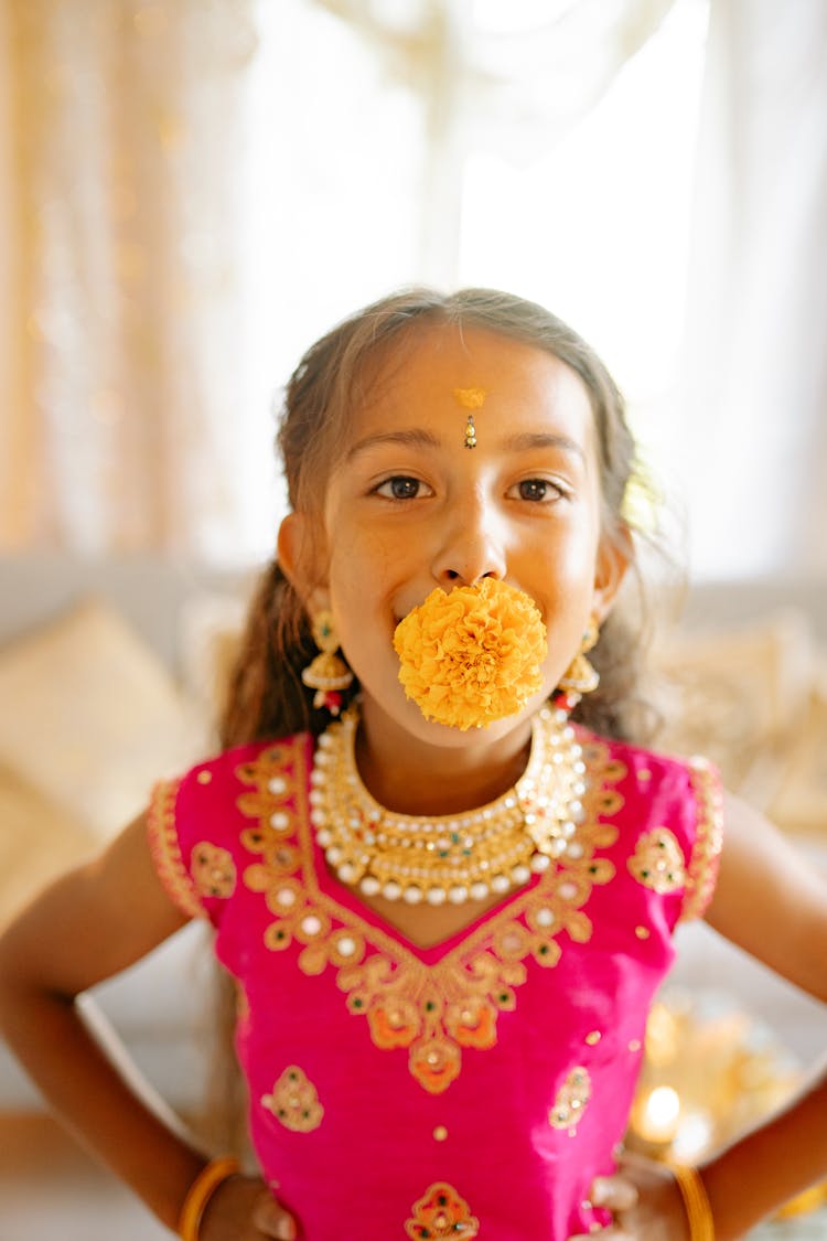 Girl Wearing A Pink Sari Biting A Yellow Flower 