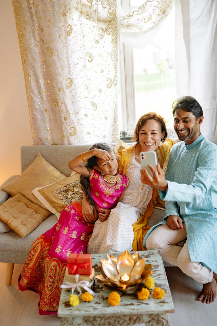 A Happy Family Sitting On The Couch While Taking Selfie